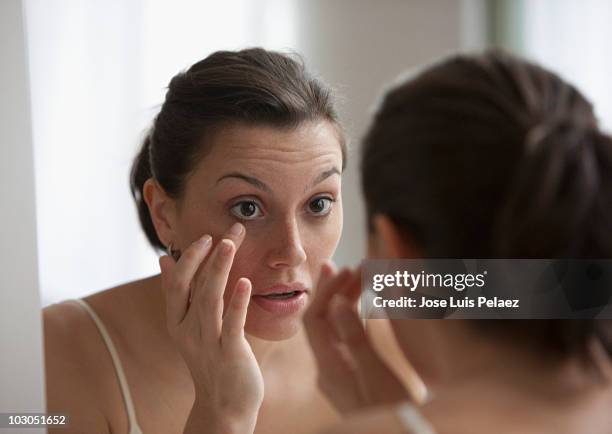 young woman checking her eye in the mirror - touching eyes stock pictures, royalty-free photos & images