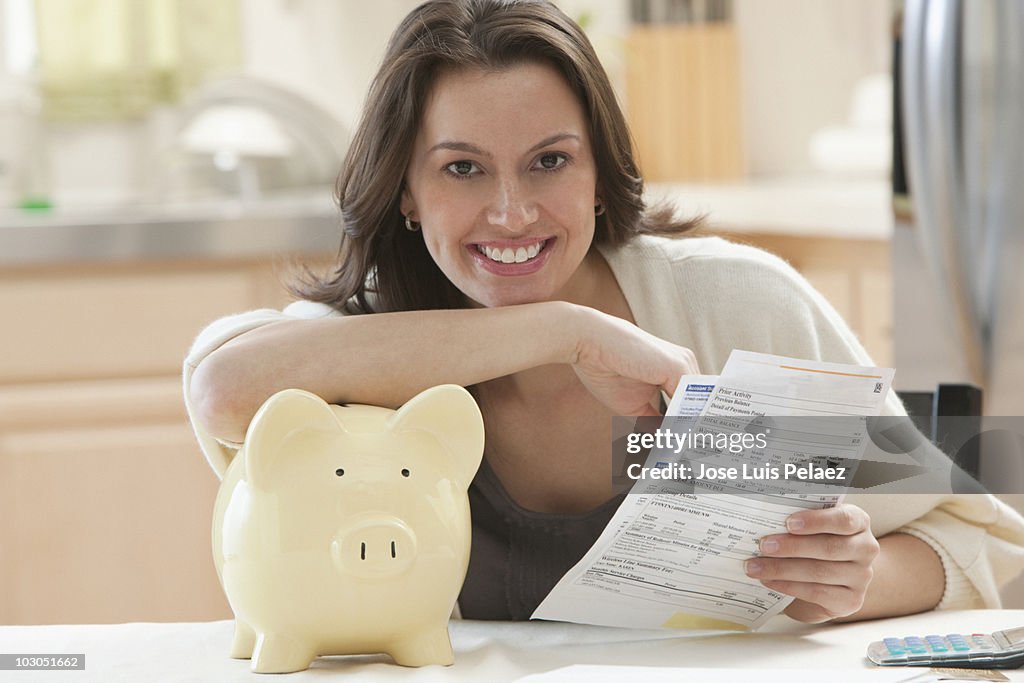 Young woman holding bills and piggy bank