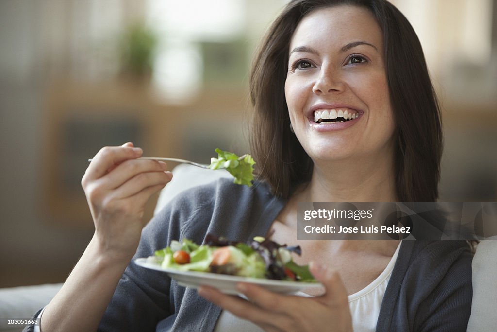 Young woman eating salad smiling