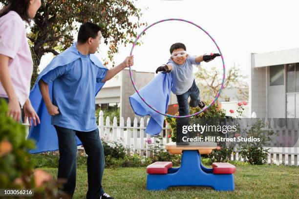 korean boy in superhero costume jumping through hoop - class hula hoop stockfoto's en -beelden