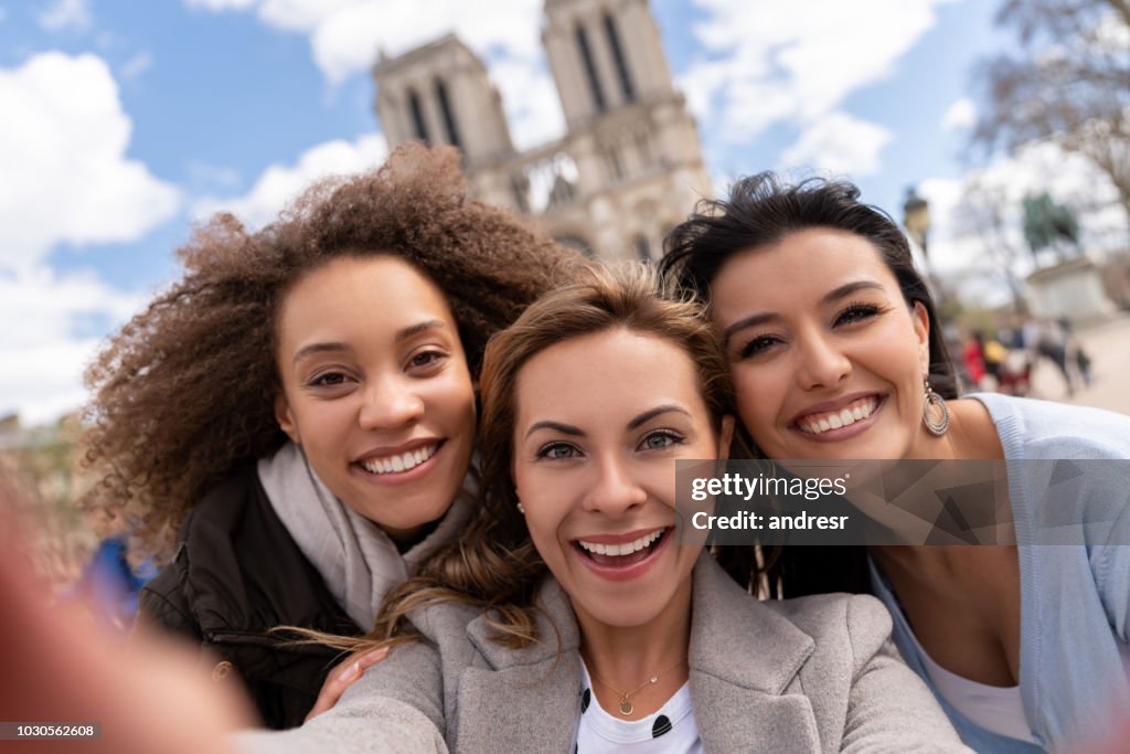 Group of friends traveling in Paris and taking a selfie at Notre-Dame