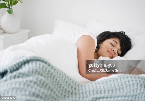 hispanic woman sleeping in bed - sleeping woman stockfoto's en -beelden