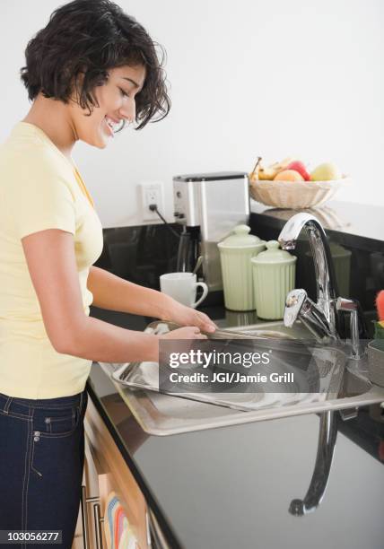 hispanic woman washing pan in kitchen - tablett oder küchenblech stock-fotos und bilder