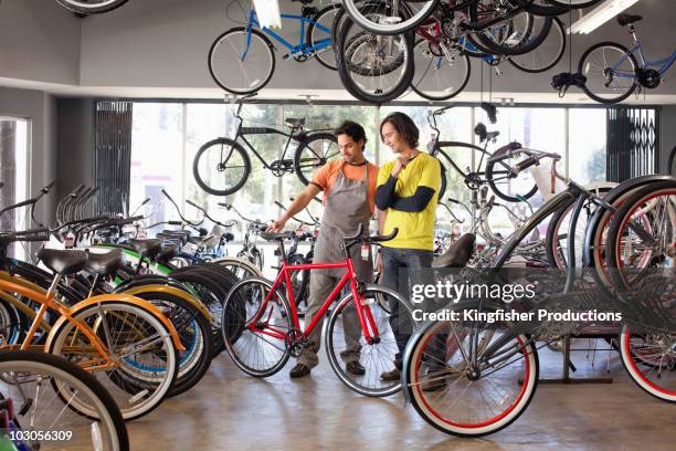 bike shop owner helping customer choose bicycle - buying a bike bildbanksfoton och bilder