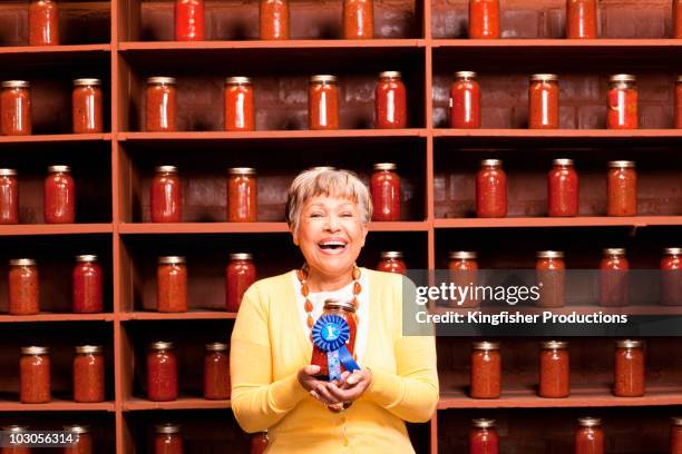 african american woman holding prize-winning jar of sauce - concurso fotografías e imágenes de stock