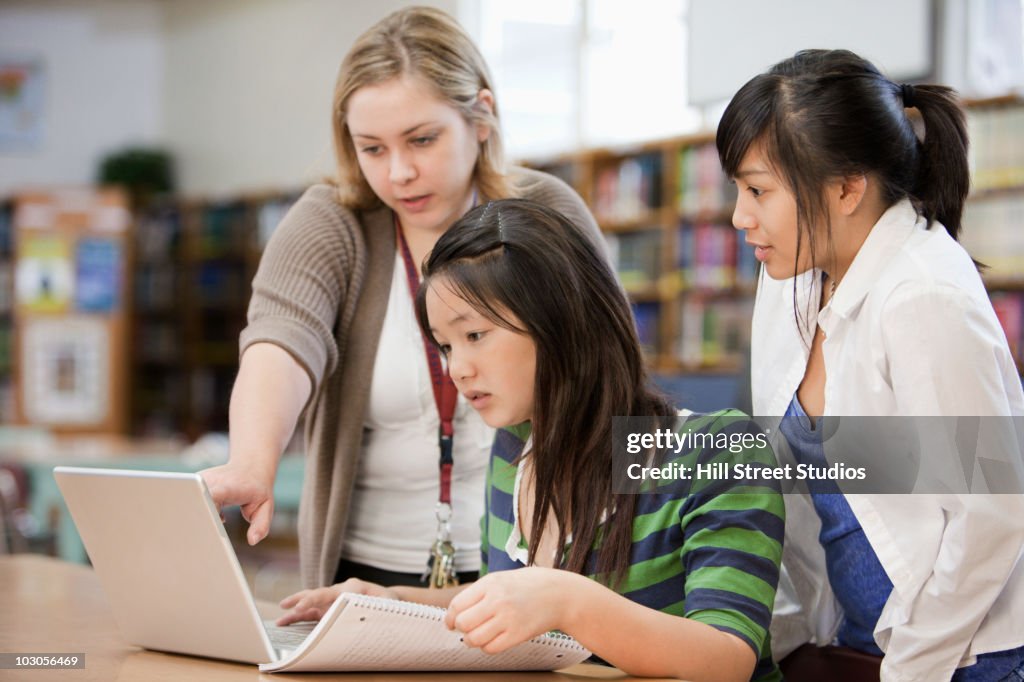 Librarian helping students with research in school library