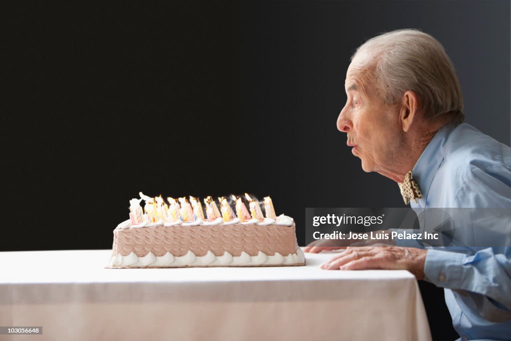 Senior Hispanic man blowing out birthday candles