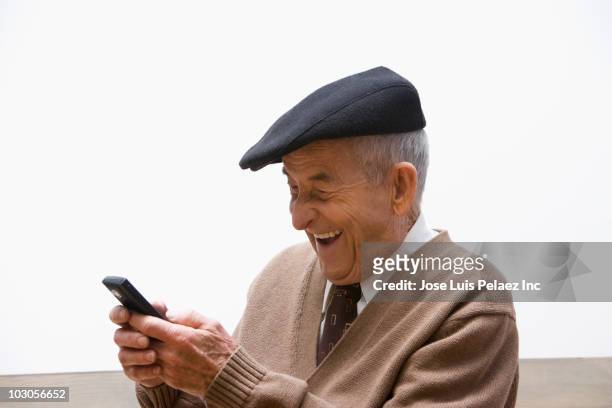 senior, hispanic man text messaging on cell phone - solo un uomo foto e immagini stock