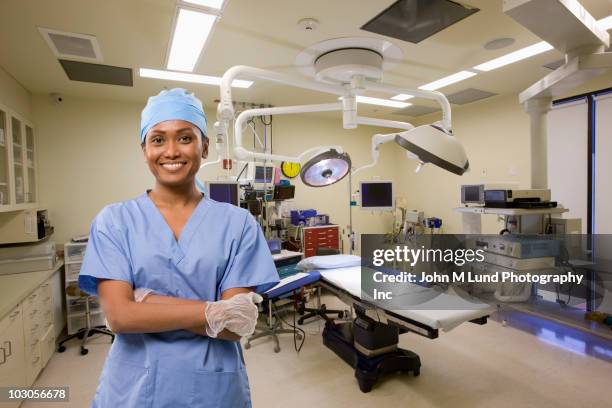 mixed race surgeon standing in operating room - chirurgenkappe stock-fotos und bilder