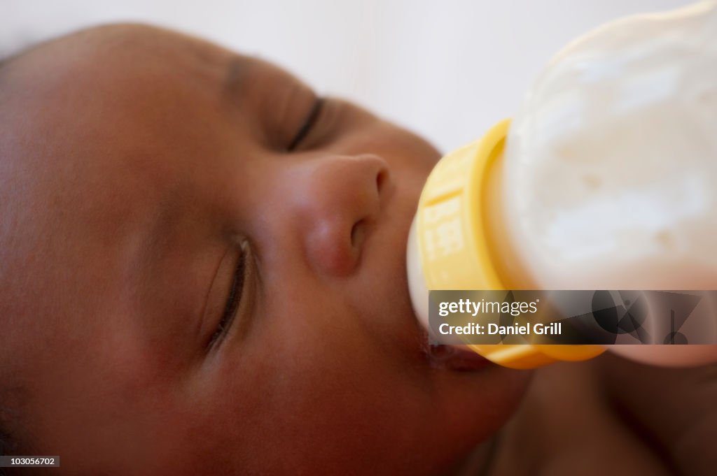 Newborn Black baby drinking from bottle