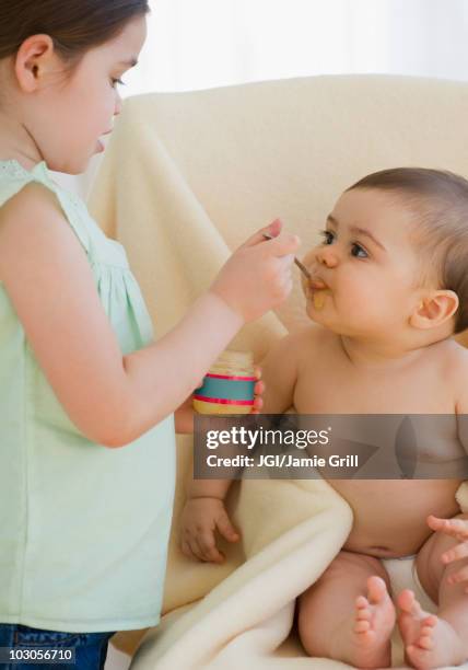 mixed race girl feeding baby brother - sisters feeding stockfoto's en -beelden