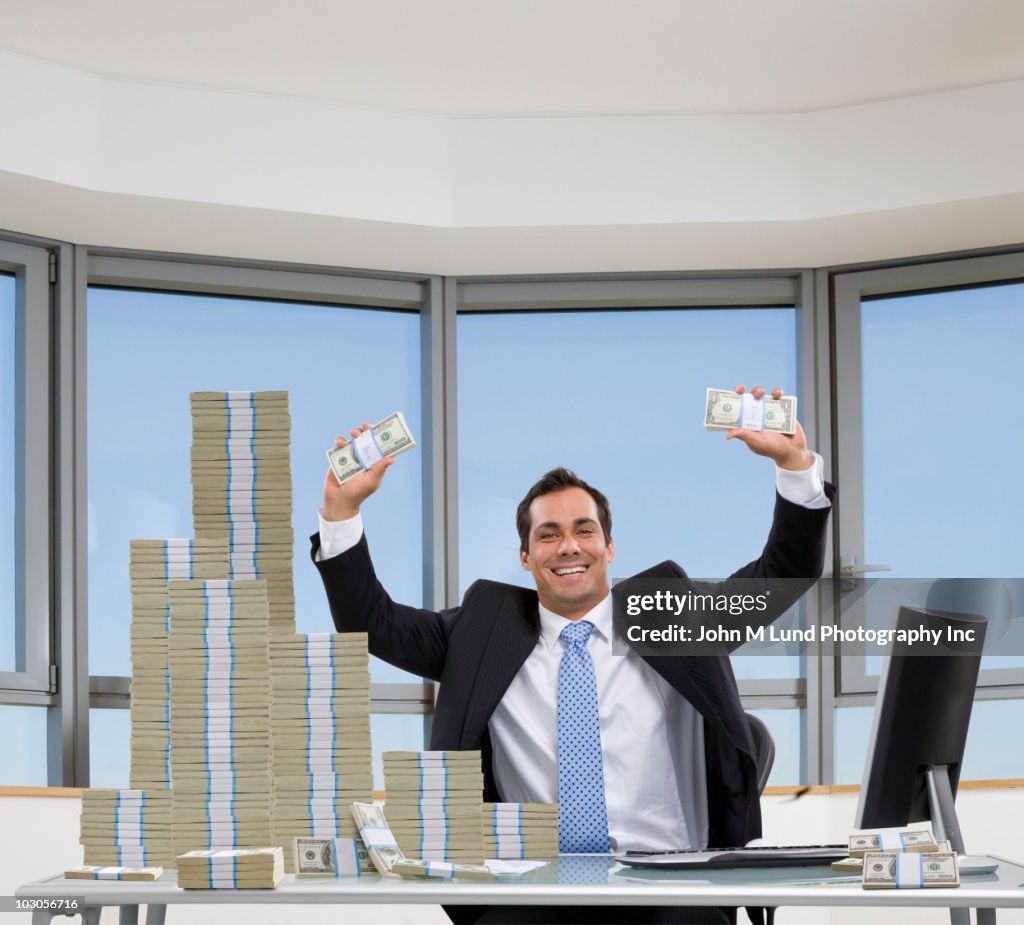 Pacific Islander businessman sitting with stacks of money