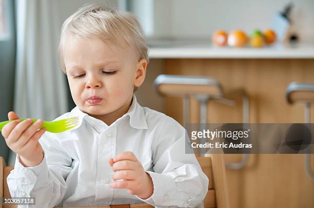 boy eating with a fork and making a face - unangenehmer geschmack stock-fotos und bilder