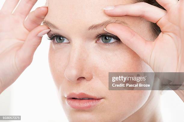 close-up of a woman rubbing eyebrows - eyebrow stock-fotos und bilder