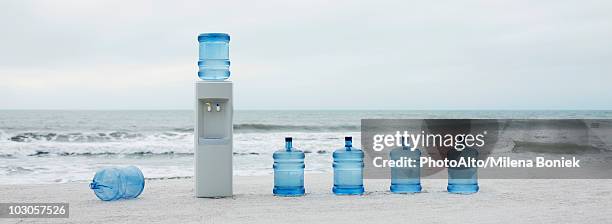 water cooler and water jugs lined up on beach - water cooler stock pictures, royalty-free photos & images