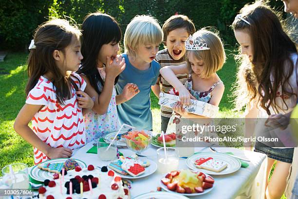 girl opening gift at birthday party as friends watch - open day 7 stockfoto's en -beelden