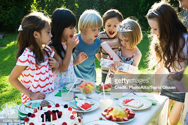 girl opening gift at birthday party as friends watch - open day 7 stock pictures, royalty-free photos & images