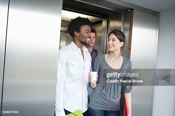 businesswoman holding a disposable cup and talking to her colleague - brussles lift stock-fotos und bilder