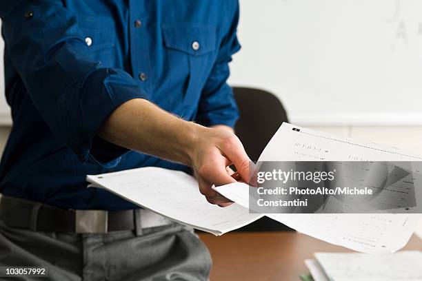 teacher handing out classwork assignment - exam papers stock pictures, royalty-free photos & images