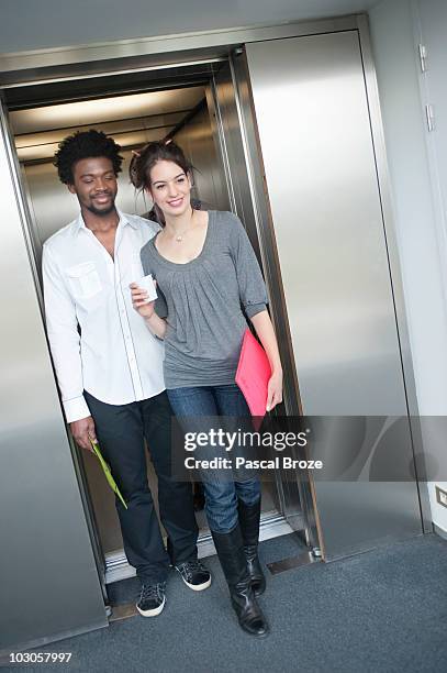 businesswoman coming out from an elevator with her colleague - brussles lift stock-fotos und bilder