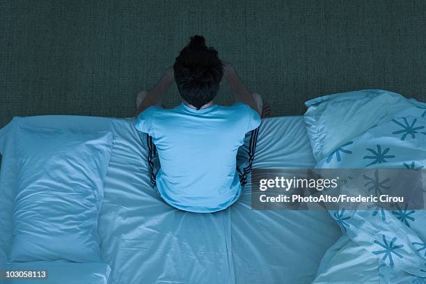 man sitting on bed unable to sleep - man worried sitting stock-fotos und bilder