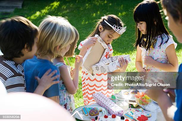 girl opening gift at birthday party as friends watch - boy tiara stock pictures, royalty-free photos & images