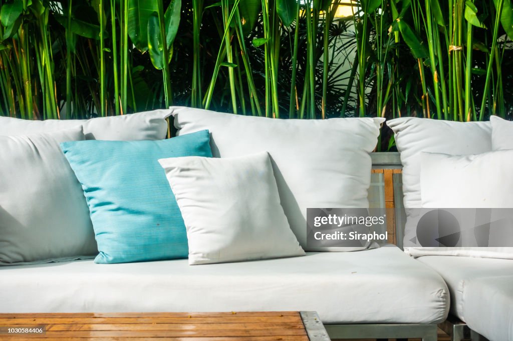 White Sofa Bed In Yard Against Bamboos