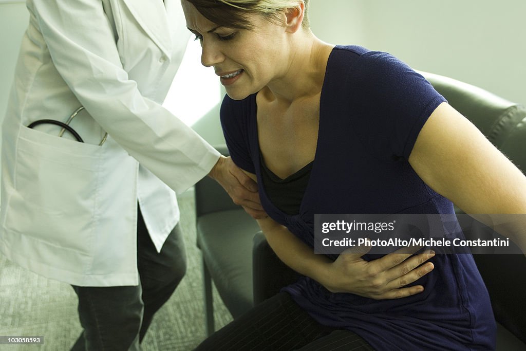 Doctor assisting patient with severe abdominal pain