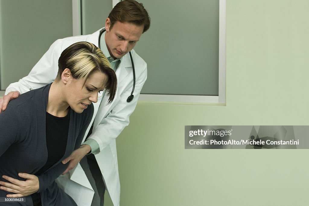 Doctor assisting patient experiencing severe abdominal pain