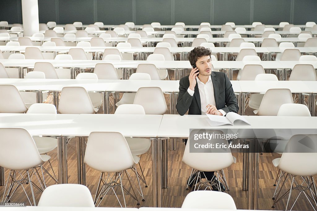 Businessman sitting at a cafeteria and talking on a mobile phone