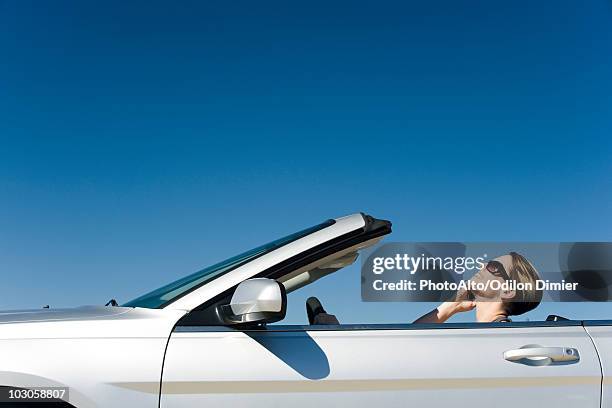 woman talking on cell phone while driving convertible - car side stock pictures, royalty-free photos & images