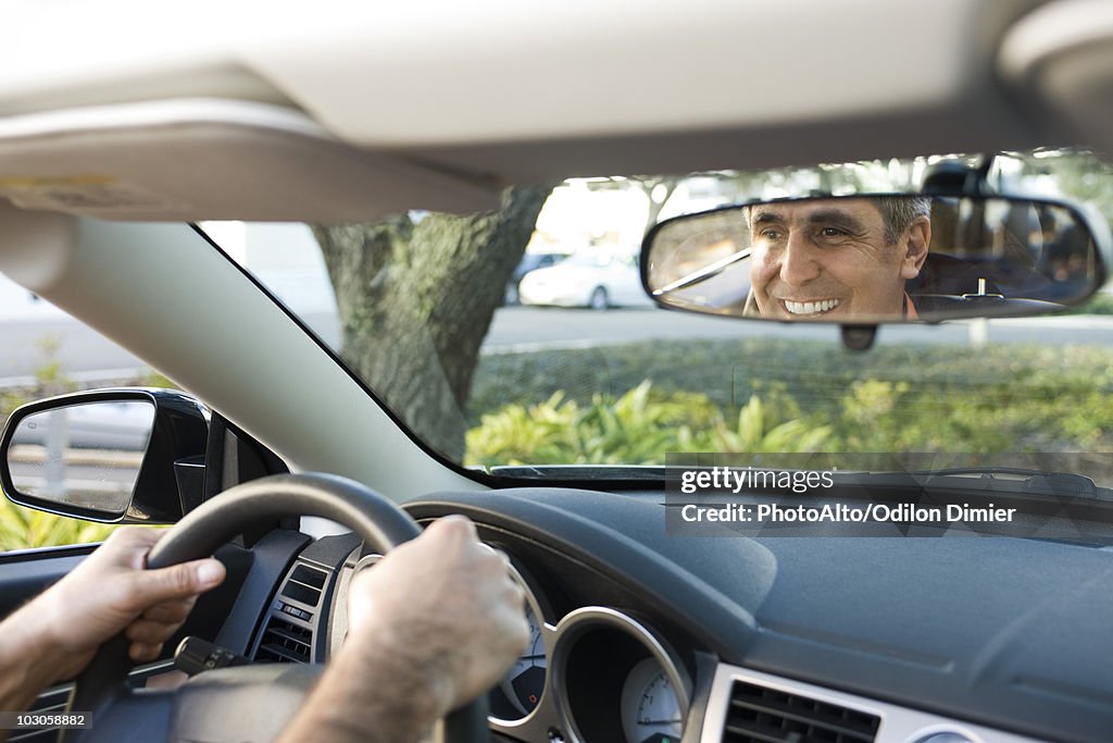 Man driving, reflection in rearview mirror