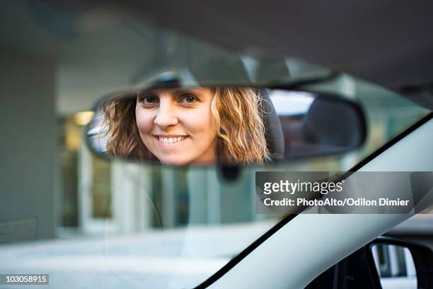 woman's face reflected in rearview mirror - fahrzeugspiegel stock-fotos und bilder