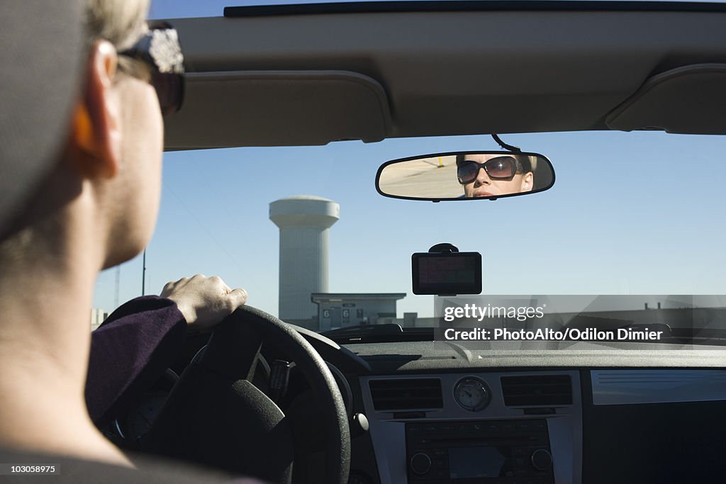 Woman driving, reflection in rearview mirror