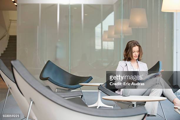 businesswoman sitting on a chair and reading a magazine - magazine table stock pictures, royalty-free photos & images