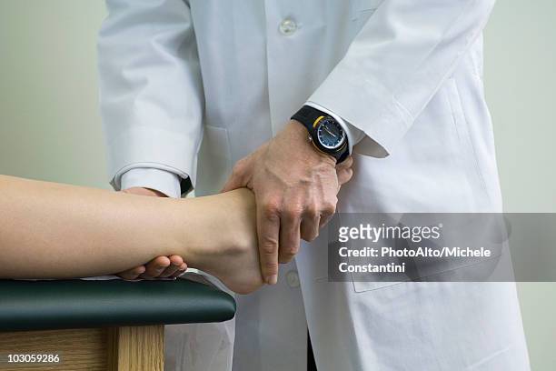 doctor examining patient's feet and ankle - ankle stock-fotos und bilder