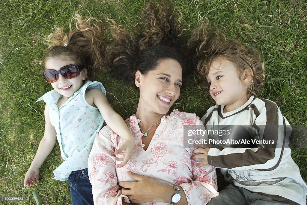 Mother lying on grass with young children