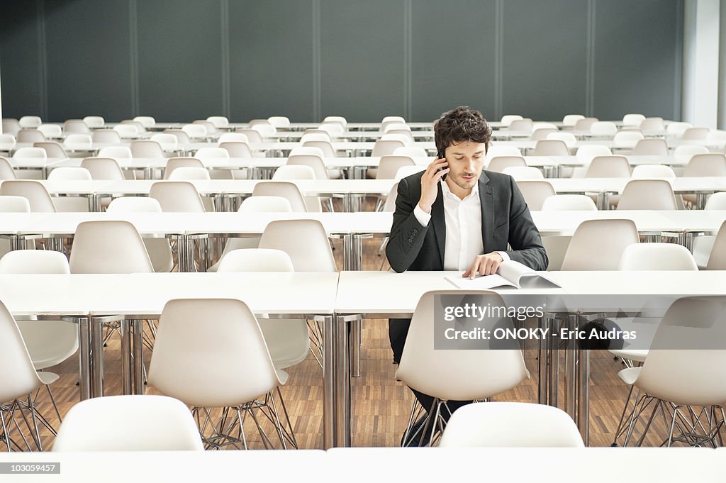 Businessman sitting at a cafeteria and talking on a mobile phone