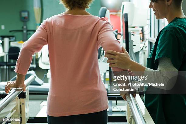 patient undergoing rehabilitation walking exercises with assistance from physical therapist - rehab stock pictures, royalty-free photos & images