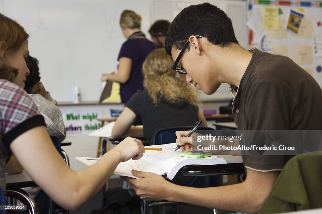 High school student helping classmate with assignment