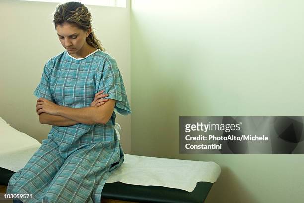 female patient sitting on examination table waiting for doctor - examination table stock pictures, royalty-free photos & images
