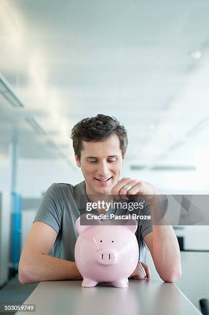Businessman Inserting A Coin Into A Piggy Bank, Stock-Foto