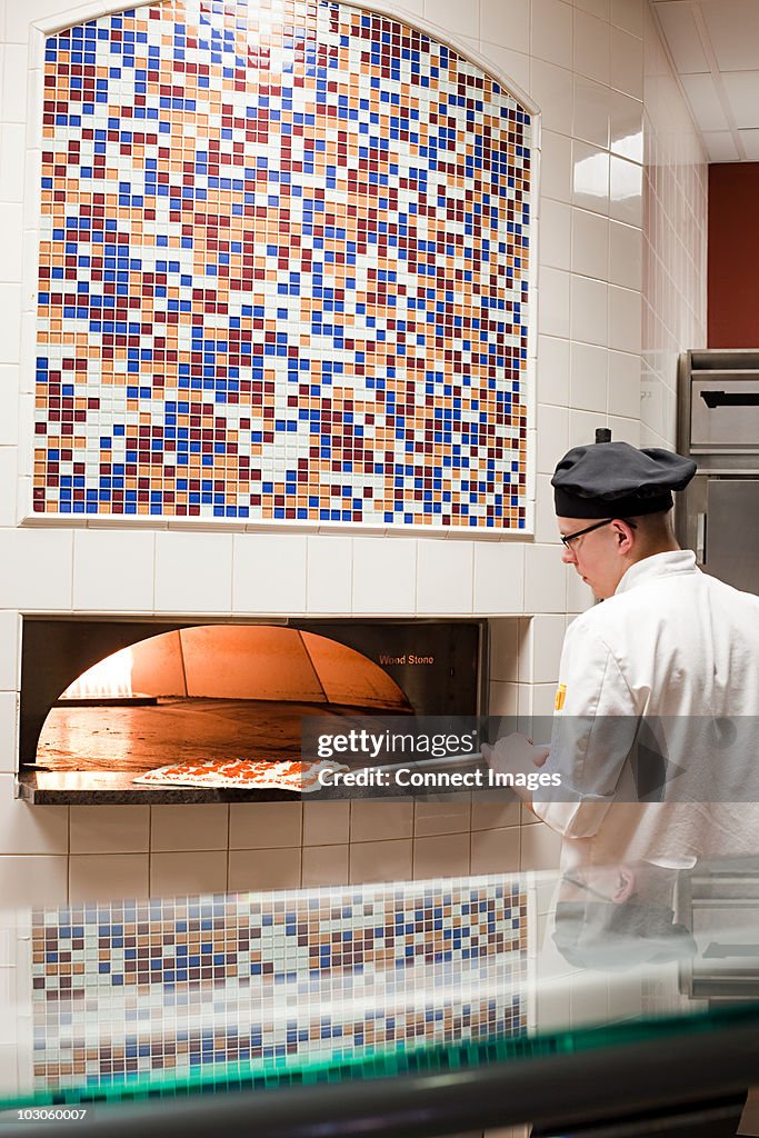 Male chef making pizza in commercial kitchen