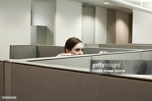 woman hiding behind cubicle in office - verstopt stockfoto's en -beelden