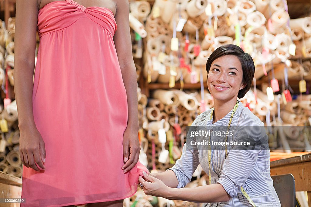 Seamstress adjusting dress on model