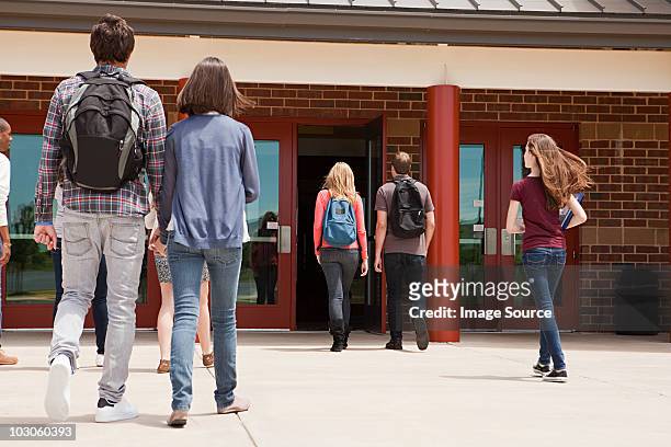 high school students entering school building - entering photos et images de collection