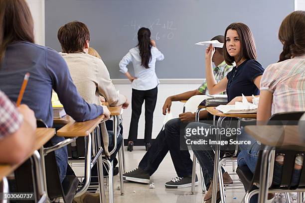 female student with paper aeroplane in classroom - ignorance photos et images de collection