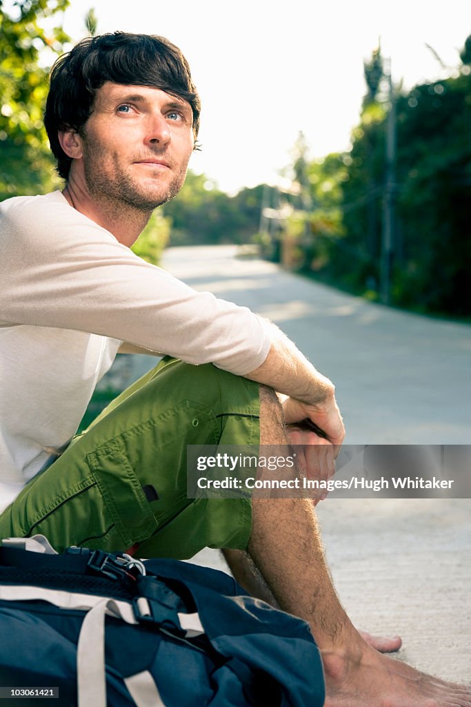 Backpacker sitting on side of road