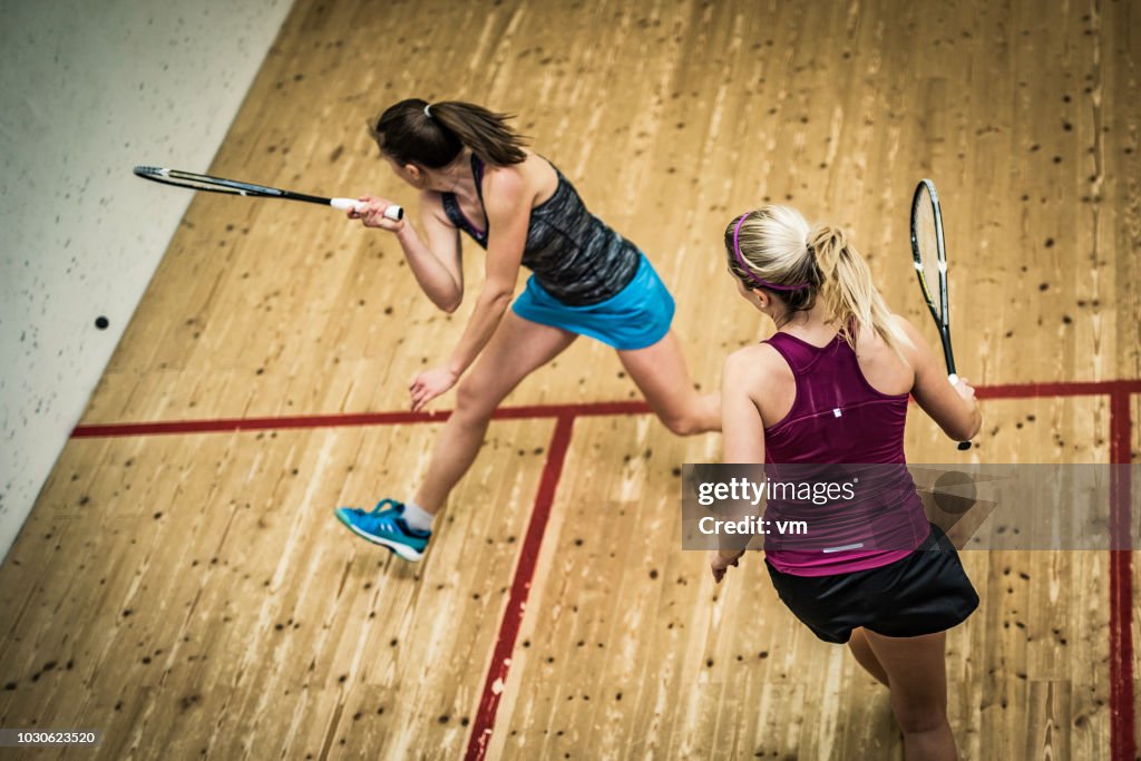 Female squash player hitting the ball