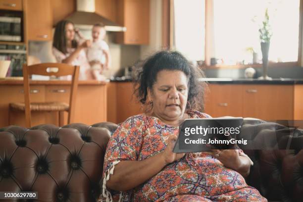 reife frau zu hause mittels digital-tablette - aboriginal woman stock-fotos und bilder